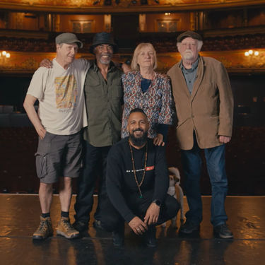 A photo of Brian Wren, Othman Read, Claire Muldoon, Roland Muldoon and Yamin Choudury posing together in the centre of Hackney Empire's stage with the auditorium behind.