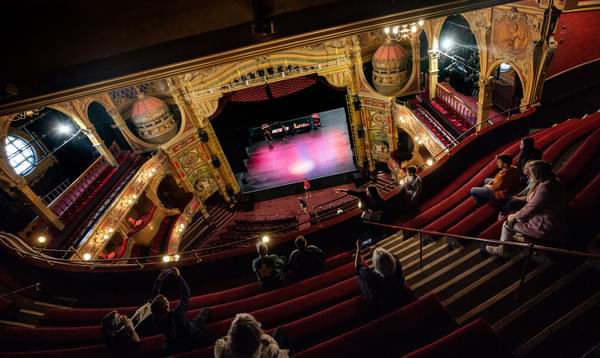 A photo taken from the Gallery in Hackney Empire, showing a member of the Hackney Empire Team delivering a Guided Tour to a group of people.