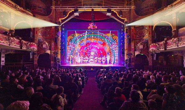 A photo of Mother Goose 2022 taking from the back of the Stalls showing a full audience sat in place watching