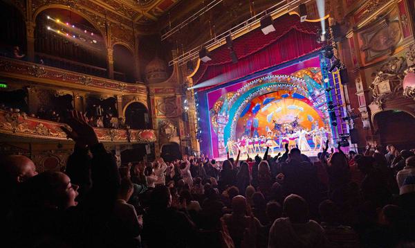 A photo taken from the back of the Stalls in Hackney Empire, showing an audience on their feet applauding Mother Goose in 2022.
