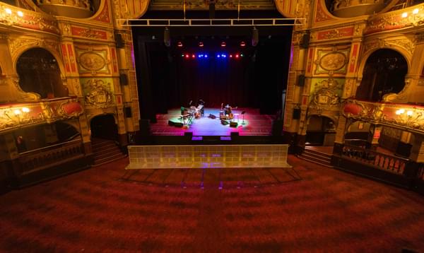 A photo taken from the Dress Circle showing the Hackney Empire stage and the Stalls with all of the seats taken out