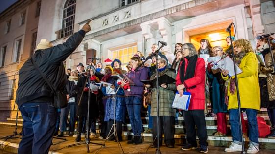 A photo of Hackney Empire community choir performing on the steps of Hackney Town Hall at Christmas time