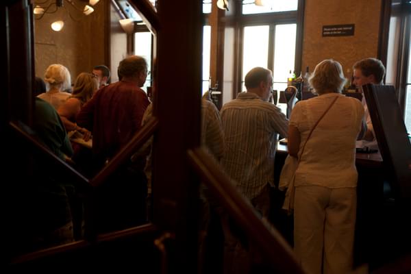 A photo taken through the doors looking into the Dress Circle bar, showing people waiting to collect their drinks.