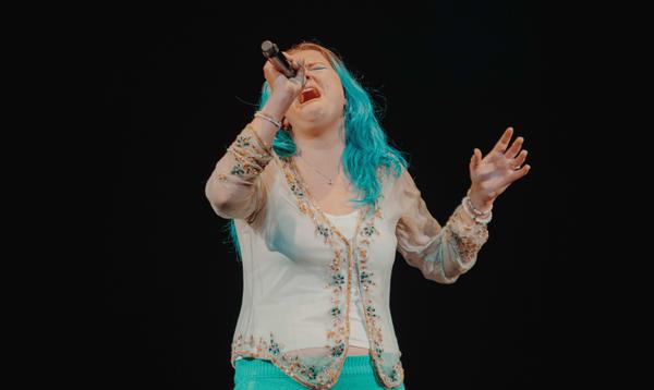 Blewska has blue hair and is singing into the microphone