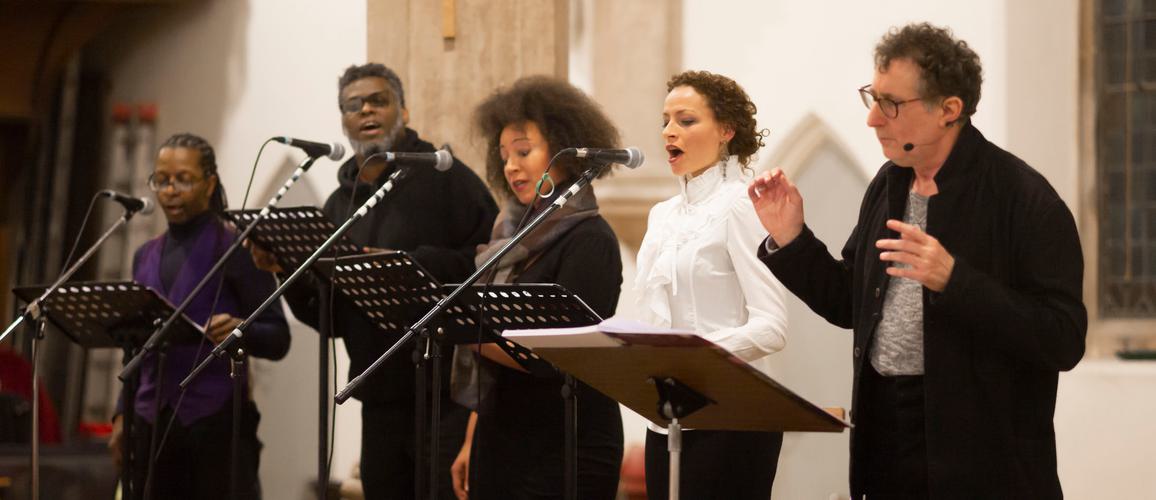 The Sun Does Shine soloists performing with the conductor. All are lined up and singing together.