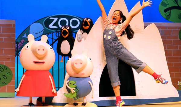 Peppa and George pig are standing outside the zoo with one of their friends and two penguins.