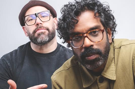Tom Davis and Romesh Raganation are looking close into the camera