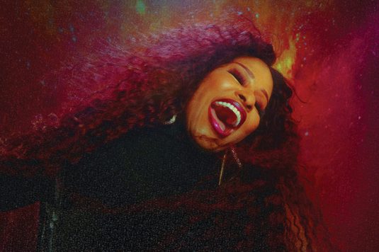 A woman singing passionately against a red background