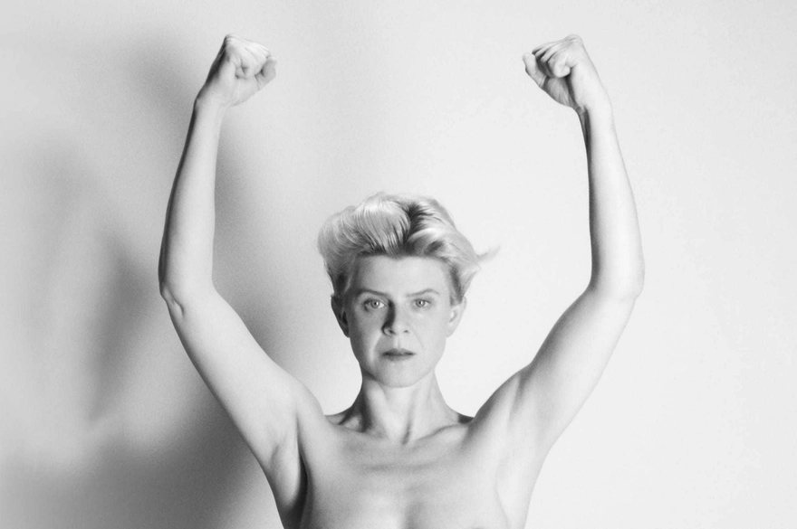 Robyn poses with her arms up, conveying a sense of empowerment and openness in a simple environment.