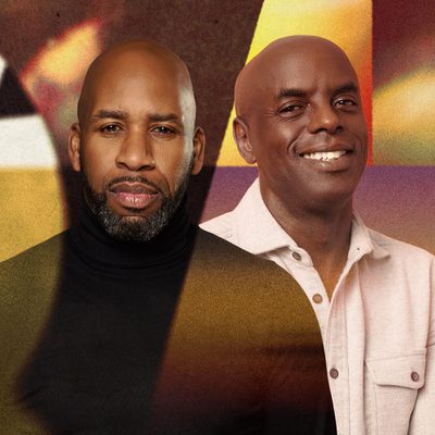 Two men are standing next to each other, both smiling warmly, showcasing a friendly connection.