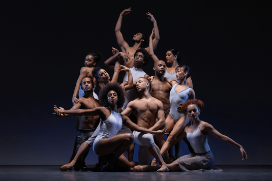 A group of dancers strikes a pose for a photo, displaying their colorful attire and enthusiastic expressions.