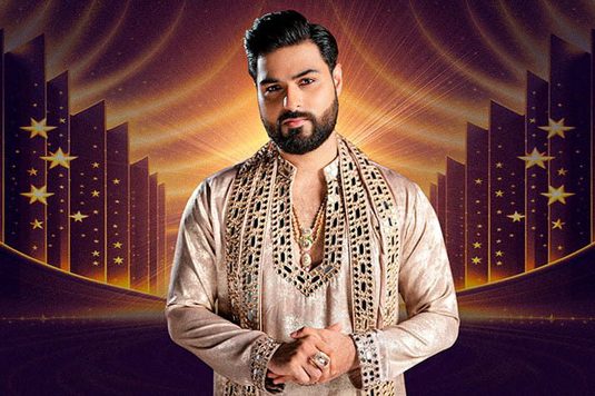 A man in embroidered traditional attire stands confidently with a gentle smile. The background features a starry, radiant design, creating a majestic tone.