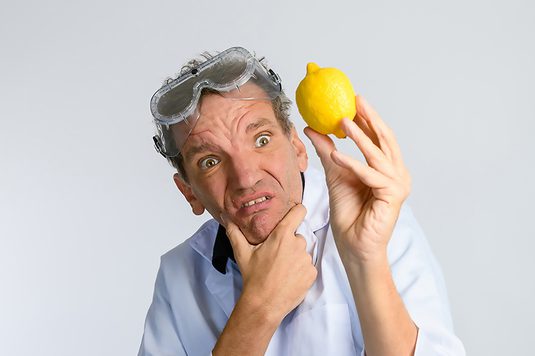 Henning When is wearing a lab coat is holding a lemon, possibly for a scientific experiment or demonstration.