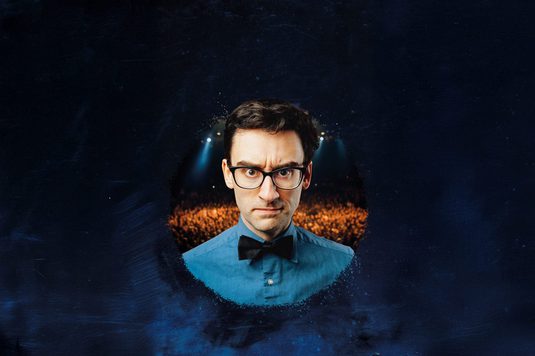 MC Hammersmith is wearing glasses, a blue shirt, and a black bow tie looks straight into the camera with a mean look on his faceMC Hammersmith is wearing glasses, a blue shirt, and a black bow tie looks straight into the camera with a mean look on his face