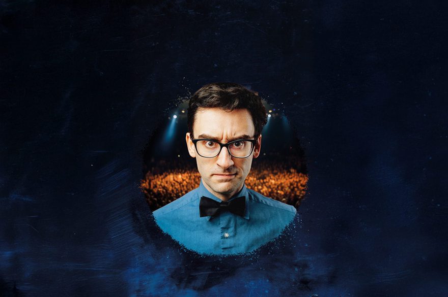 MC Hammersmith is wearing glasses, a blue shirt, and a black bow tie looks straight into the camera with a mean look on his faceMC Hammersmith is wearing glasses, a blue shirt, and a black bow tie looks straight into the camera with a mean look on his face