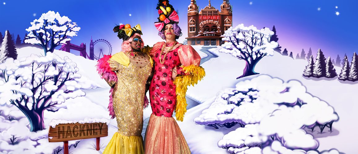 Kat B and George Heyworth as the Ugly Sisters wearing yellow and pink dresses with fruit headdresses. They pose against a snowy scene with Hackney Empire in the background.