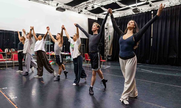 The Cinderella Ensemble posing together holding hands up in the air