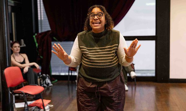 Jade Johnson as the Fairy Godmother has both hands out and a happy expression on her face