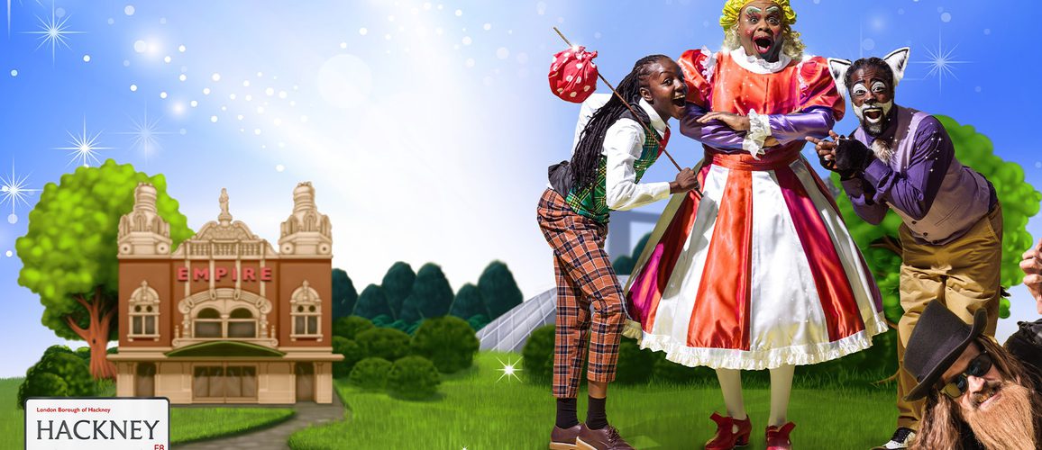 Kandaka Moore as Dick Whittington, Clive Rowe as Sarah the Cook and Kat B as Tommy the Cat are positioned against an illustrated blue background with Hackney Empire in the background. Graham MacDuff is peeking in from one corner as King Rat.