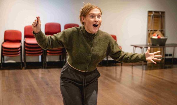 Beth Sindy as Fairy Bowbells is holding her right hand as if there's a wand in it and her left hand is outstretched, with a shocked expression on her face.