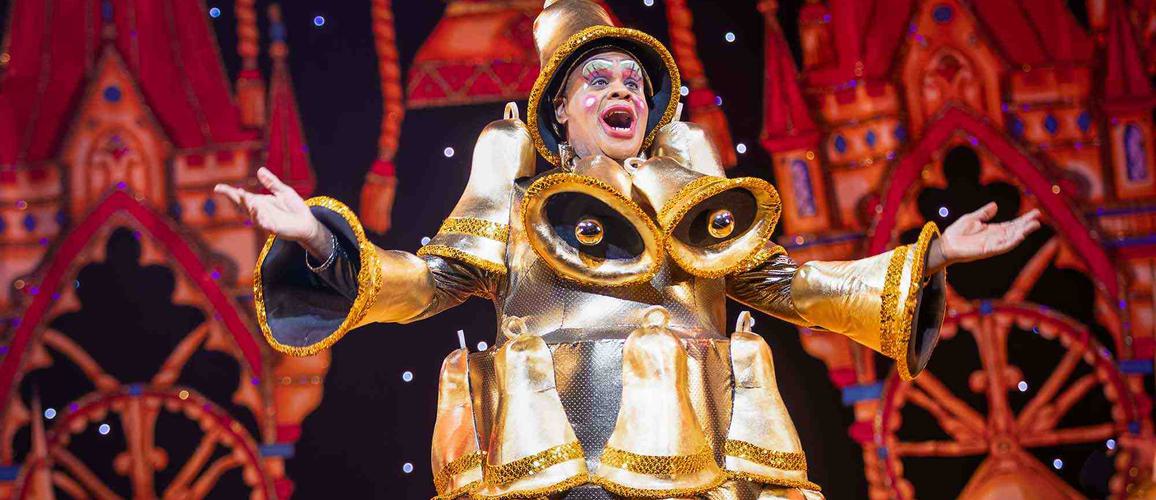 Clive Rowe as Sarah the Cook in the Finale of the show. Clive is wearing a dress completely covered in gold bells.