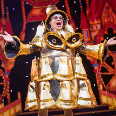 Clive Rowe as Sarah the Cook in the Finale of the show. Clive is wearing a dress completely covered in gold bells.