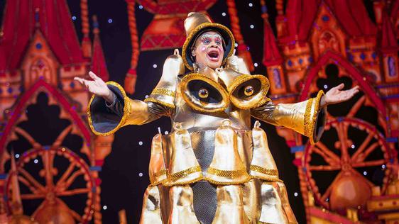 Clive Rowe as Sarah the Cook in the Finale of the show. Clive is wearing a dress completely covered in gold bells.