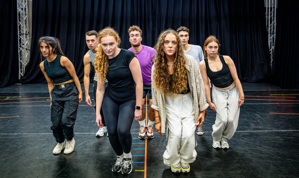 The Aladdin Ensemble in the rehearsal room. They are partly bent down and leaning to the right, staring at the camera.