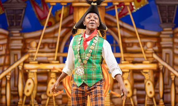Kandaka Moore as Dick Whittington is posing on a ship, wearing a black hat and looking hopefully out to the audience.