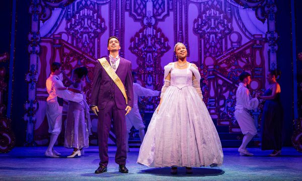 Luke Latchman as Prince Charming and Siobhan James as Cinderella stand side by side at the Ball with loving expressions on their faces.