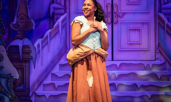 Siobhan James as Cinderella is posing smiling and looking to one side.