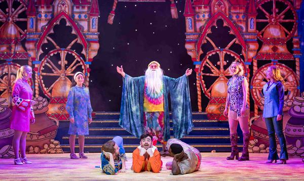 Tony Timberlake is dressed in tie-dye clothing with a long white bear as the Sultan of Swing. The Dick Whittington and his Cat Ensemble are posing around him wearing sixties/seventies clothing.