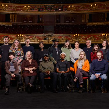 A photo of Hackney Empire Staff posing together on the main stage with the auditorium behind them.
