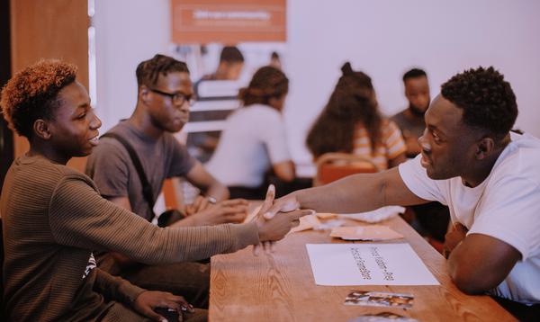 A Creative Futures workshop showing a young person shaking hands with someone over a table.