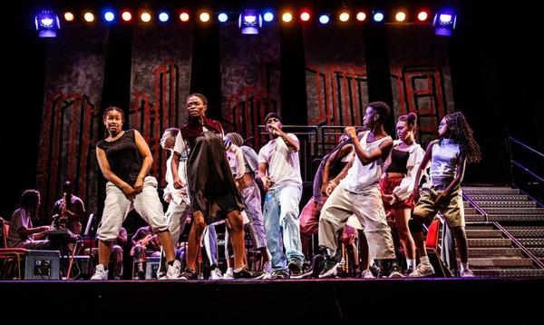 A group of dancers pose leaning away from each other in the centre of the stage.