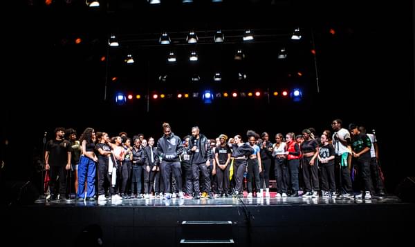 A photo of young people lined up along the front of the stage at the end of Only Joy Aloud, with Kenrick 'H20' Sandy and Yamin Choudury in the centre.