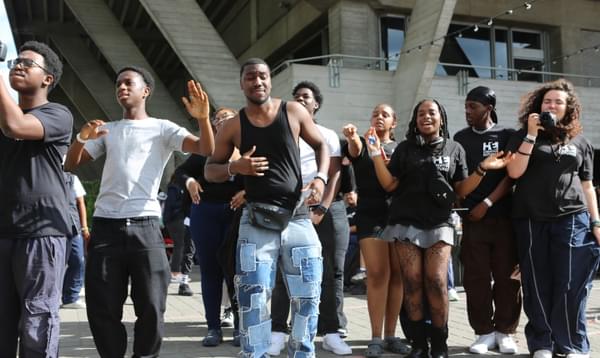 A group of young people are dancing as they watch performers at River Stage 2023 on the Southbank. Many of them are dressed in Hackney Empire t-shirts.