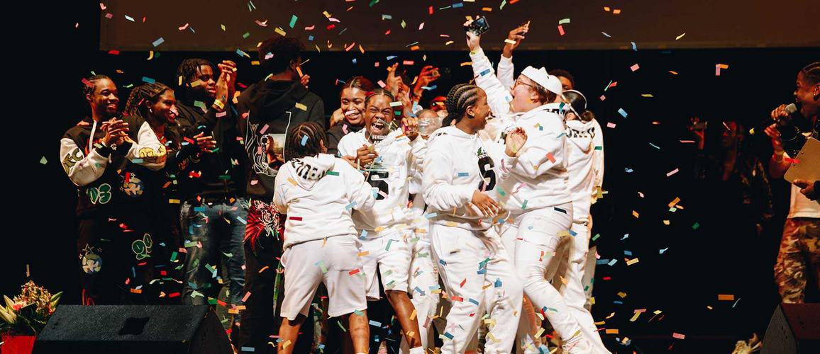 A photo showing Skadeuces, the winning dance act for Alter Ego 2023. They're all wearing white tracksuits and there are colourful streamers all around them.