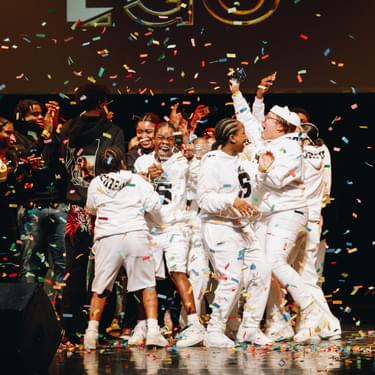 A photo showing Skadeuces, the winning dance act for Alter Ego 2023. They're all wearing white tracksuits and there are colourful streamers all around them.
