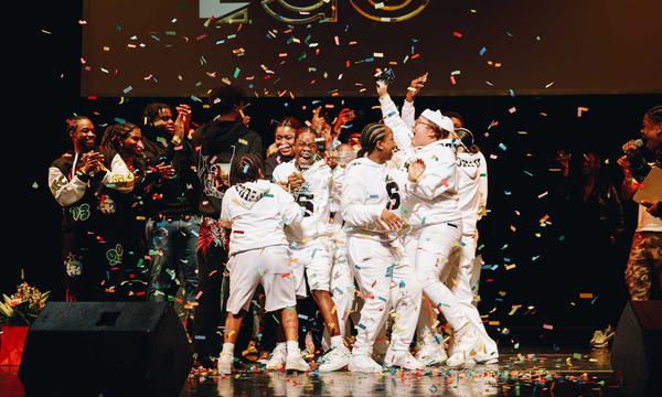 A photo showing Skadeuces, the winning dance act for Alter Ego 2023. They're all wearing white tracksuits and there are colourful streamers all around them.