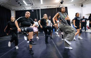 A rehearsal photo taken during our Artist Development Programme, showing young dancers moving with their right legs lifted and facing sideways.