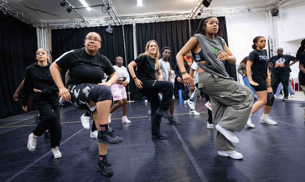 A rehearsal photo taken during our Artist Development Programme, showing young dancers moving with their right legs lifted and facing sideways.