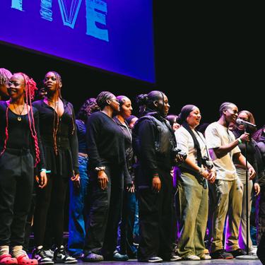 A photo of Hackney Empire Creative Futures cohort on stage together performing a piece of spoken word.