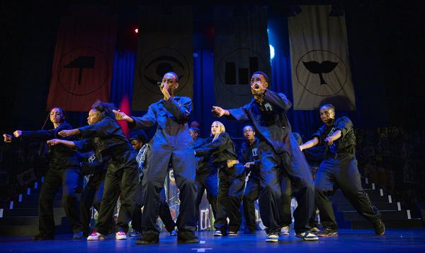Some of the dancers and rappers from the ADP 2024 Company performing together on stage in blue jumpsuits.
