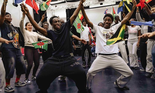 Dancers in ADP 2025 dancing together waving flags and surrounded by more of the Company