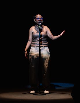 A young person is performing on the ,main stage talking into the mic while looking ahead at the audiences
