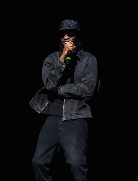 A young person wearing all black is on Hackney Empire's main stage rapping into the microphone